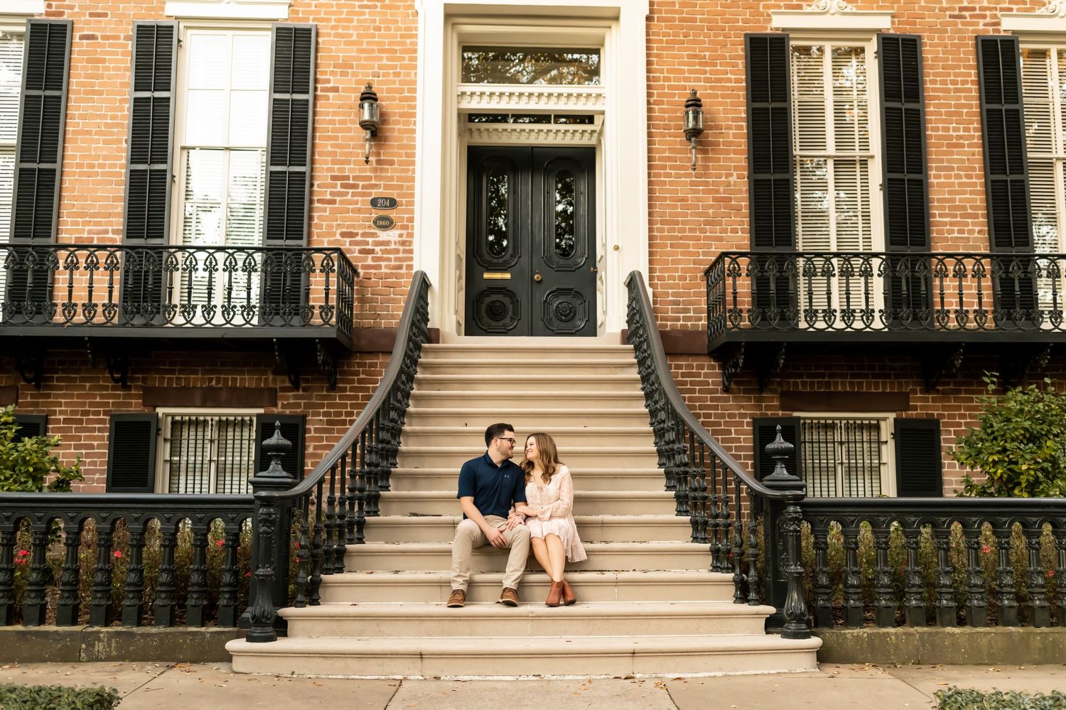 A couples sits together on historic brick building in Savannah.