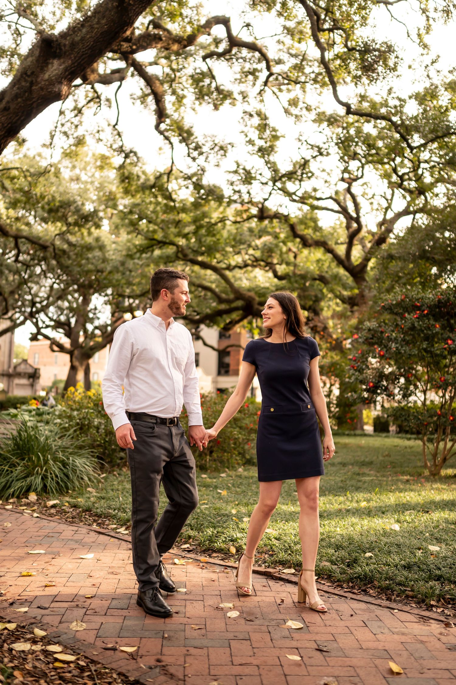 Athletic couple executing fun dance moves together in a garden setting during golden hour lighting.