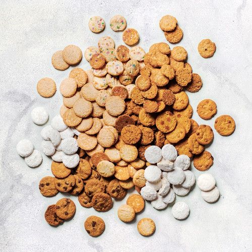 Small vanilla and chocolate cookies scattered in rows showing a gradient pattern of colors on white marble background.