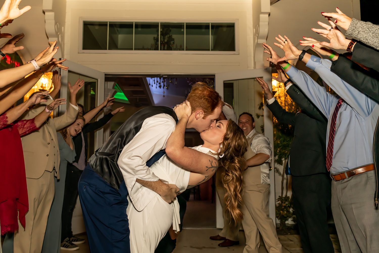 Several couples dancing in formal attire during what appears to be a wedding celebration in an indoor venue.