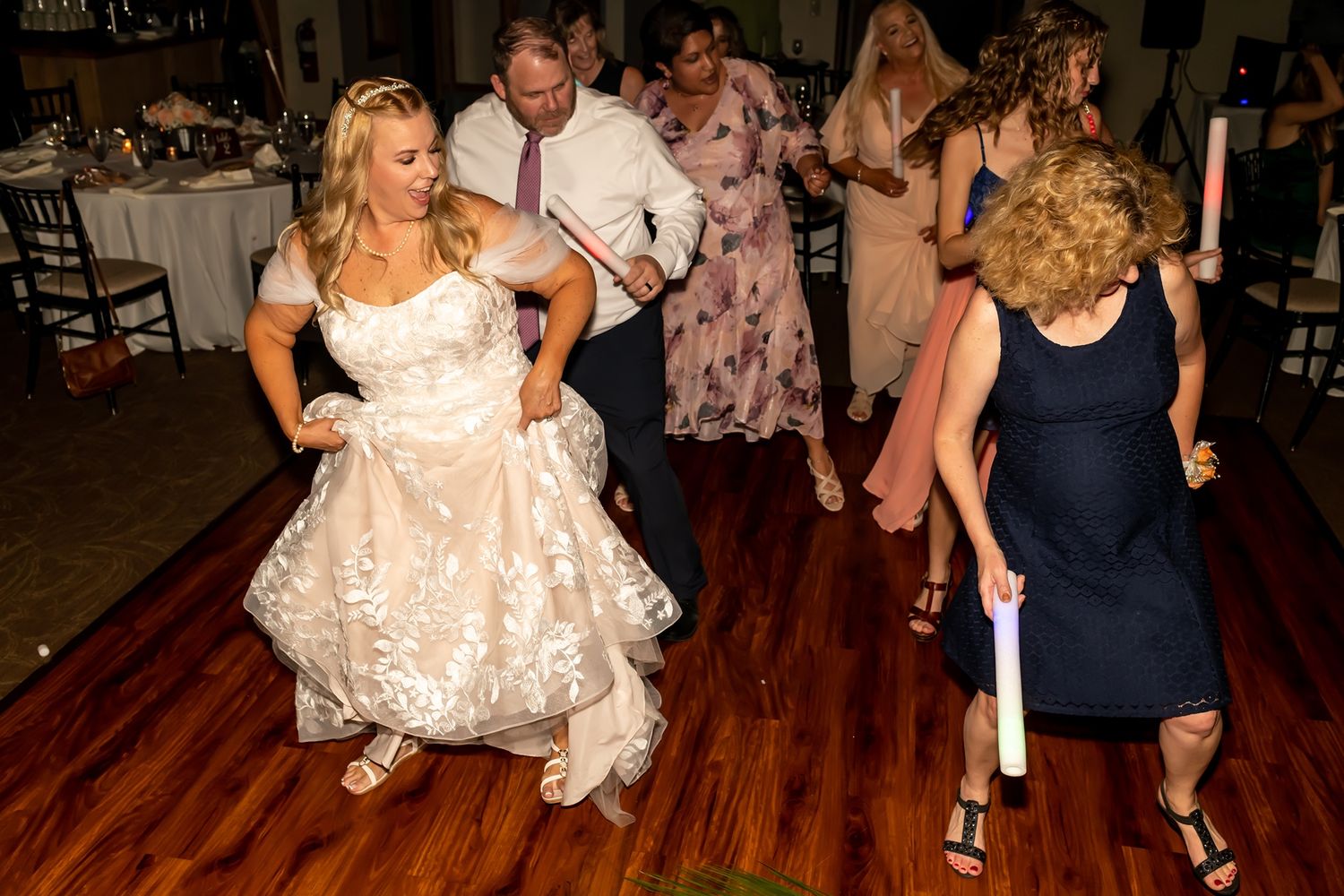 Two people dancing together on a shiny wooden dance floor during a celebration event.