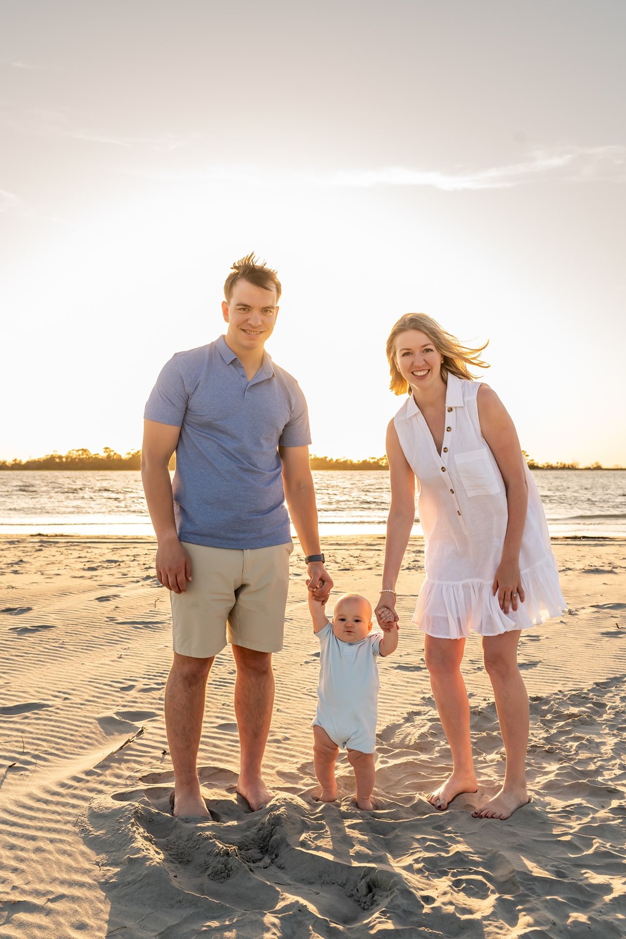 Family walking and playing together on a sandy beach at sunset with golden sunlight.
