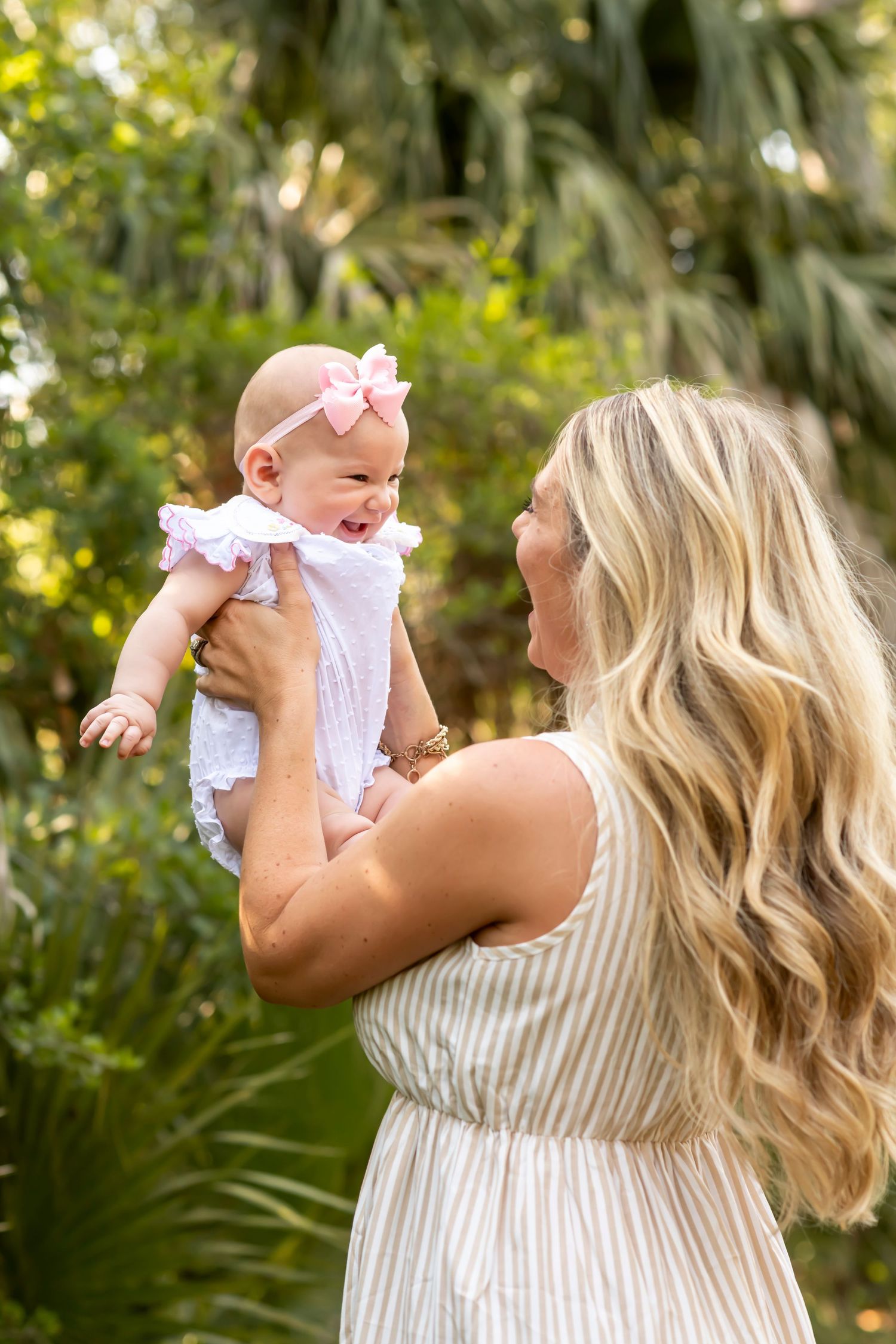 A tender moment between mom and baby outdoors surrounded by lush greenery.