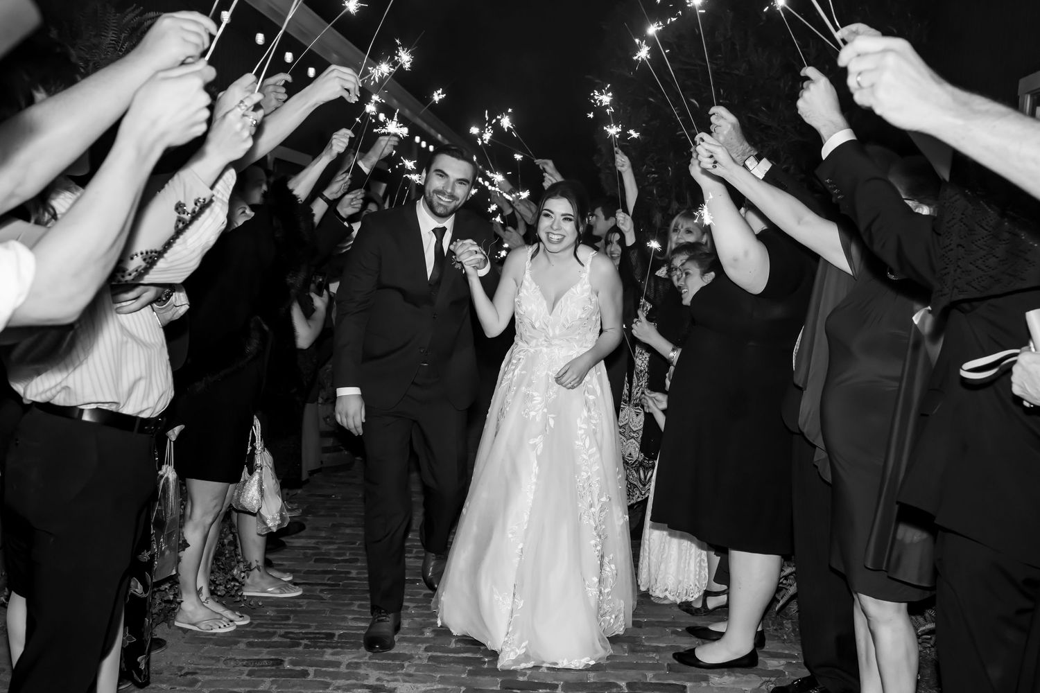 Wedding guests creating a sparkler exit tunnel at night.