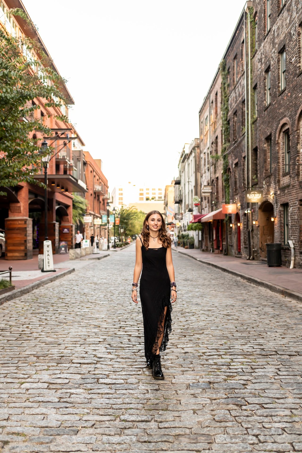 Cobblestone street in historic town lined with old brick buildings showing a walking figure in black dress in sequence.