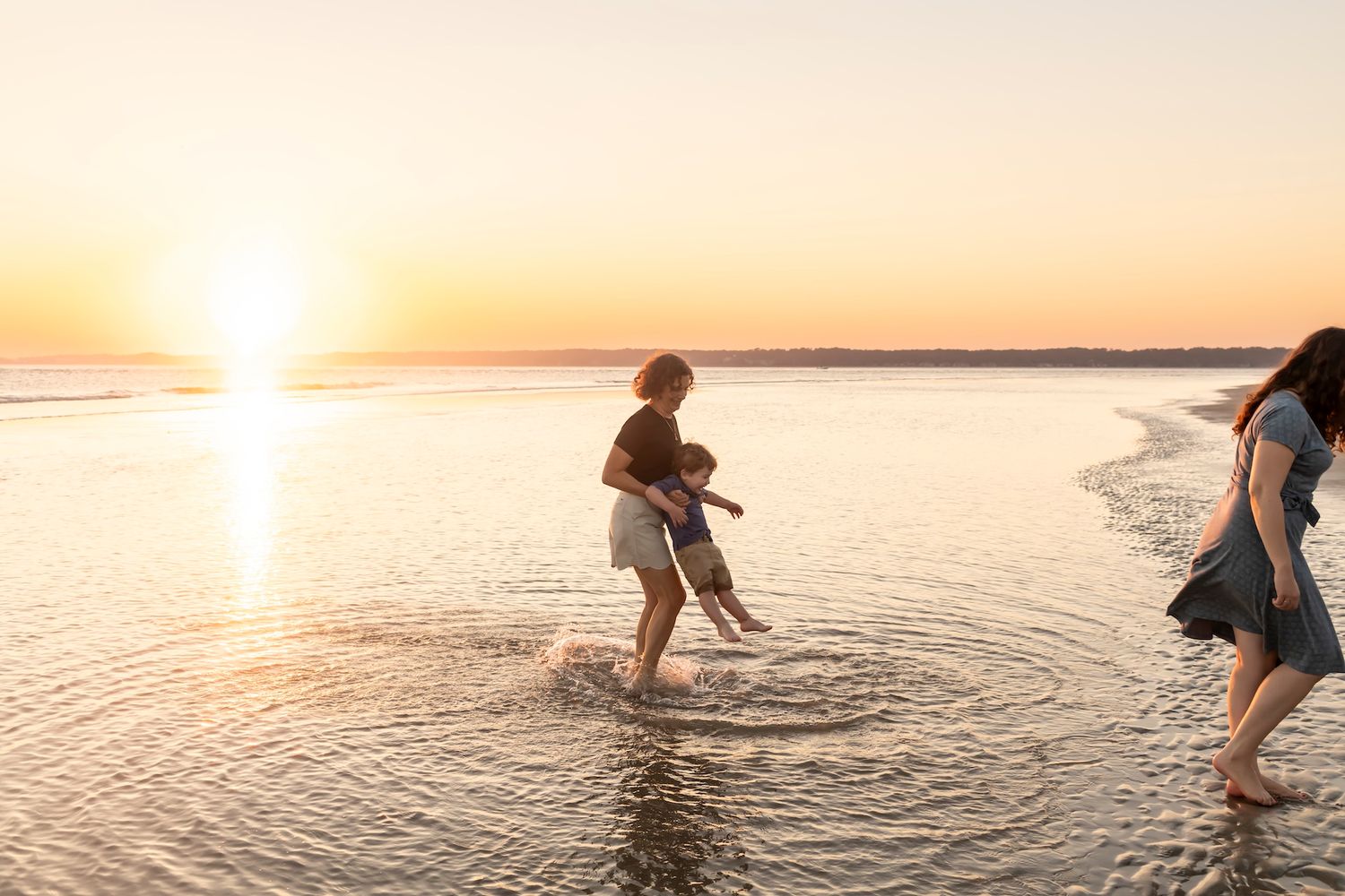 A silhouette of a person splashes water in a lake during golden hour sunset creating ripple reflections on the surface.