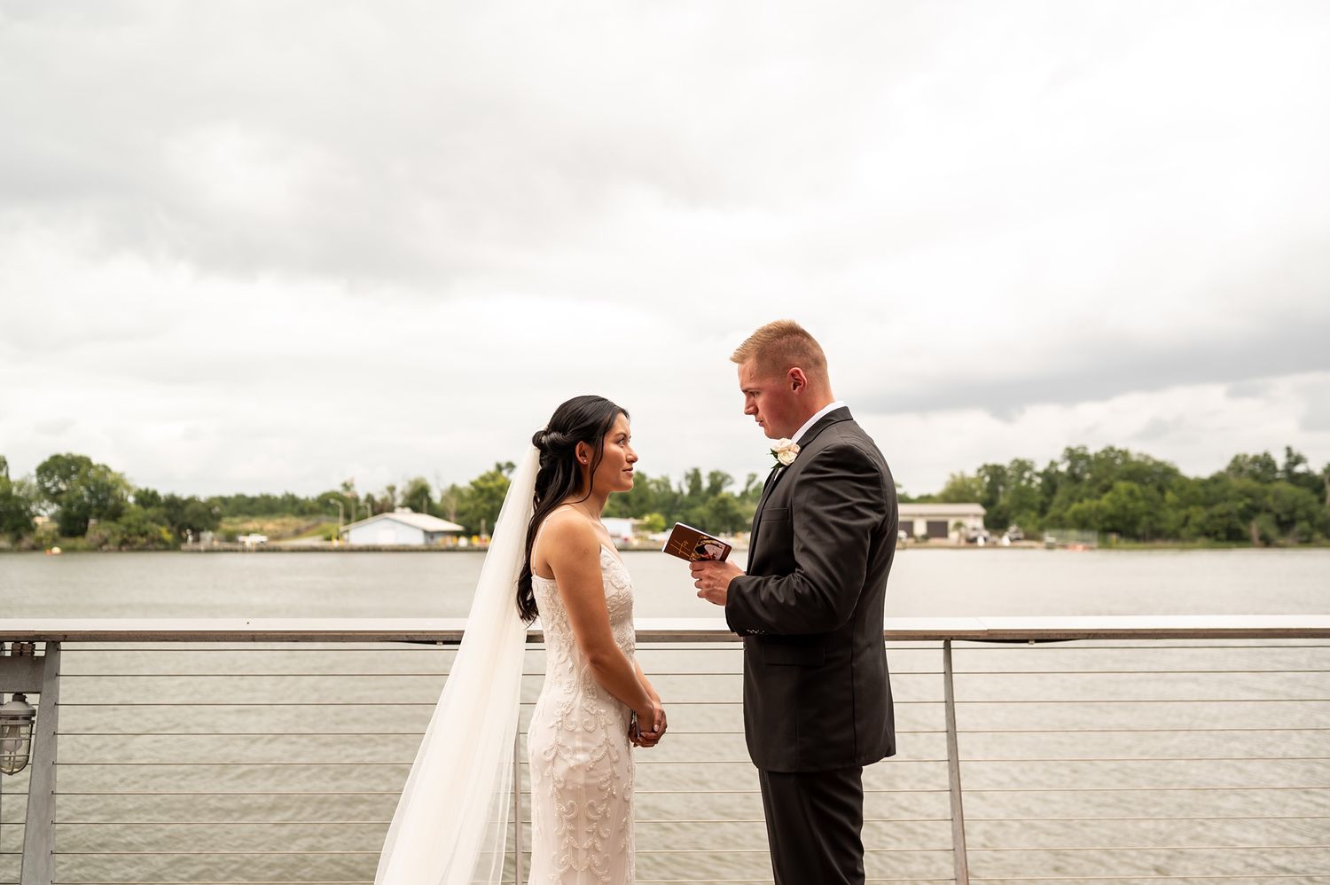 A romantic wedding couple shares vows and first kiss during their outdoor waterfront ceremony.