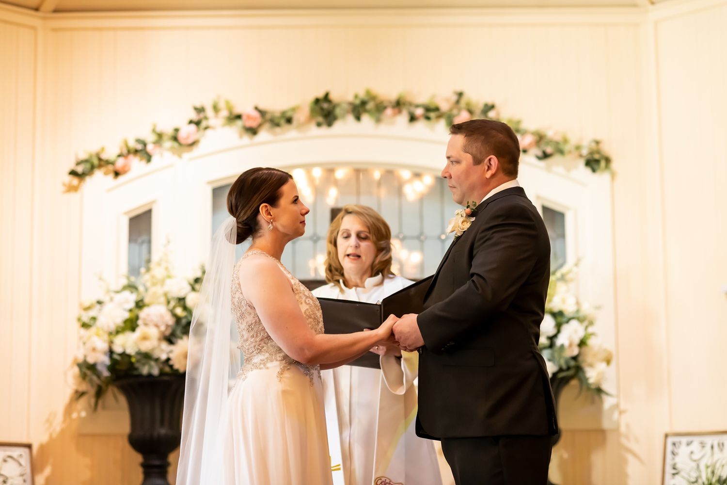 Romantic couples share tender dance moments during a wedding reception under elegant floral archways.