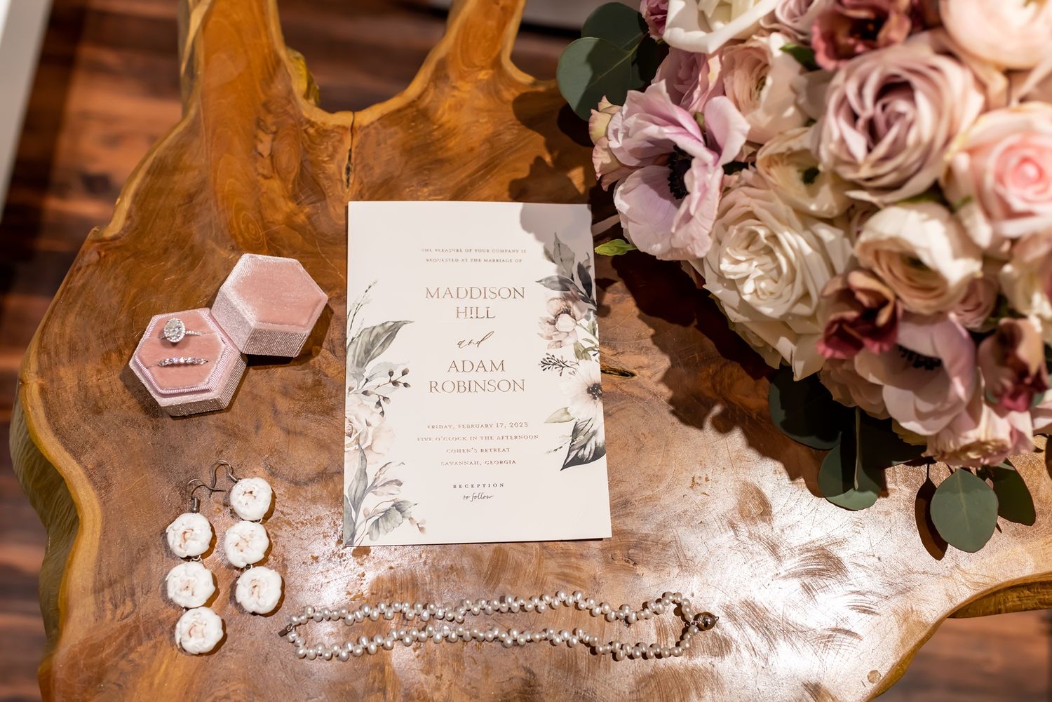 Wedding details including floral arrangements, decorative elements and elegant accessories arranged on a wooden table.