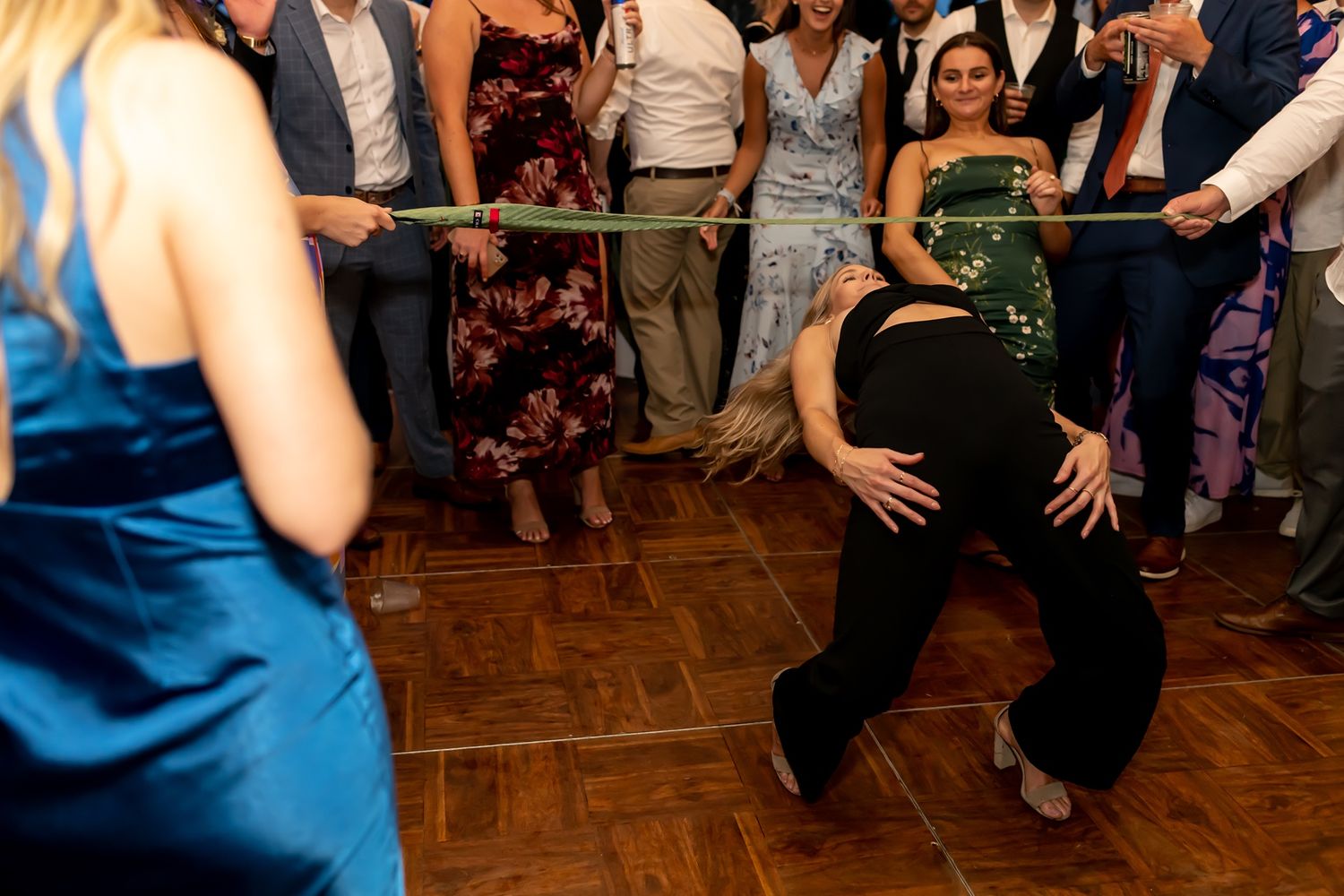 Dancers move across a wooden dance floor during an energetic wedding reception party.