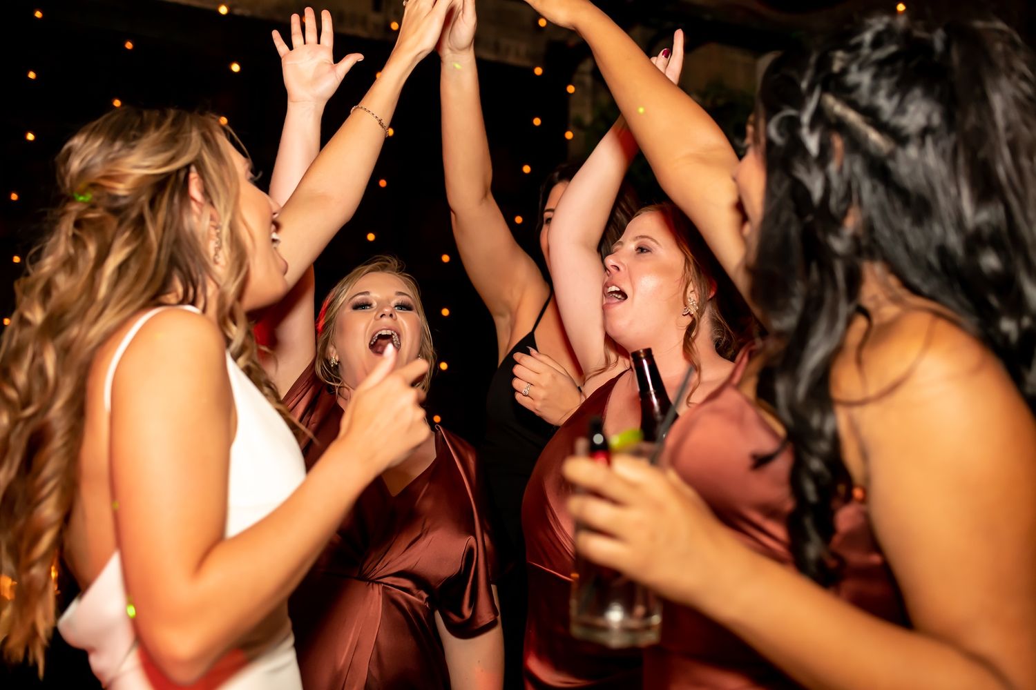 People dancing and celebrating together in a nightclub with raised hands and energetic expressions.