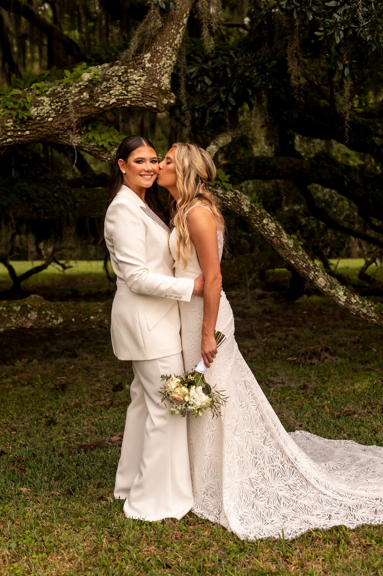 Two people share an intimate moment during a wedding photoshoot under a Spanish moss covered tree.