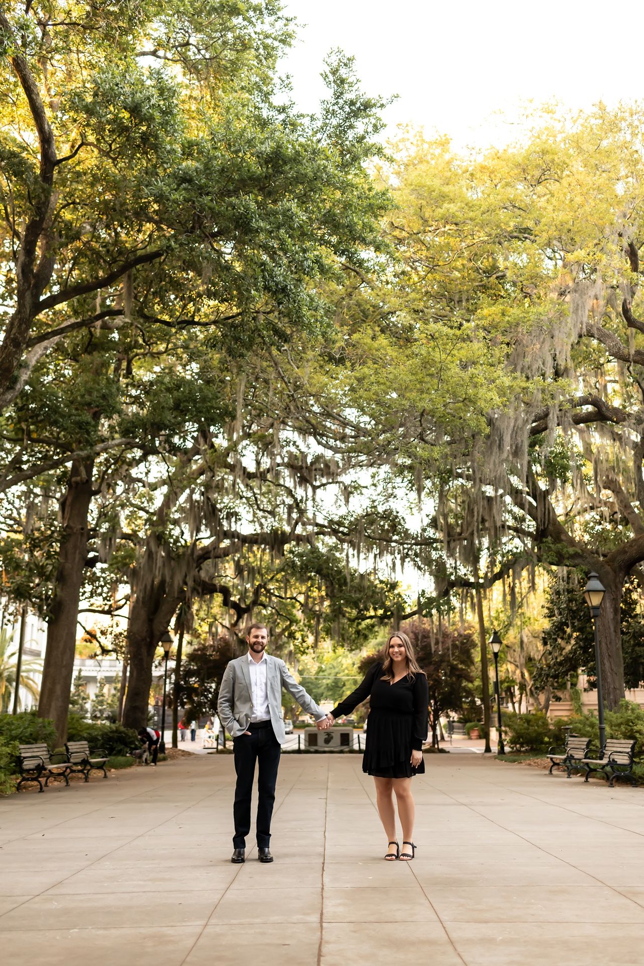 People stroll along a scenic pathway under Spanish moss-draped oak trees in a peaceful Southern park.