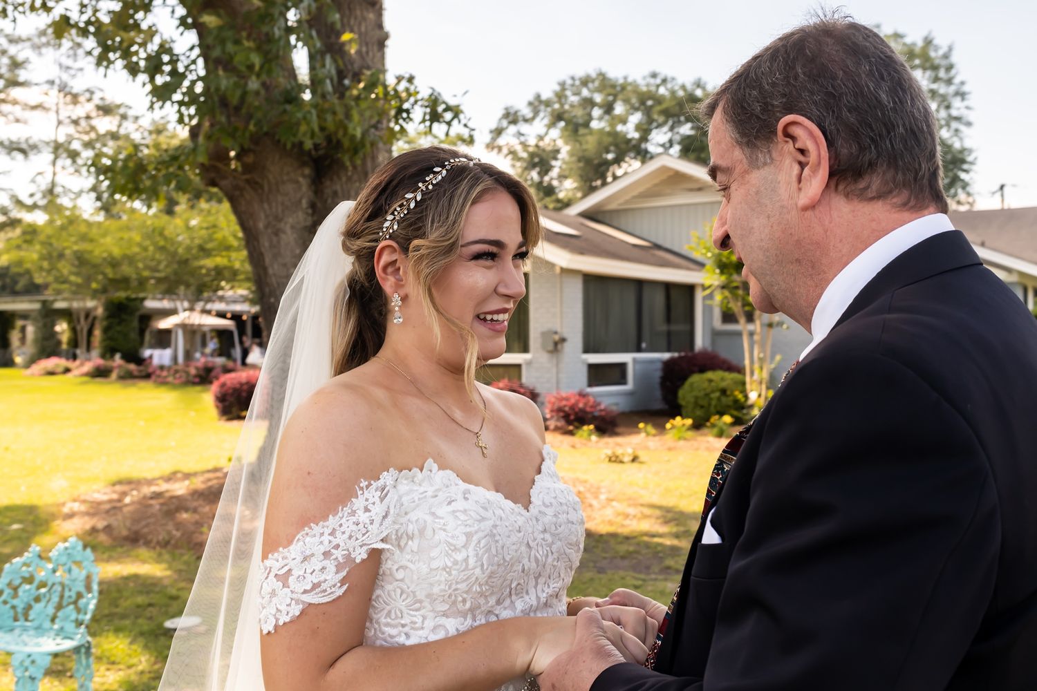 A joyful moment between two people at an outdoor wedding ceremony with a white veil and formal attire.