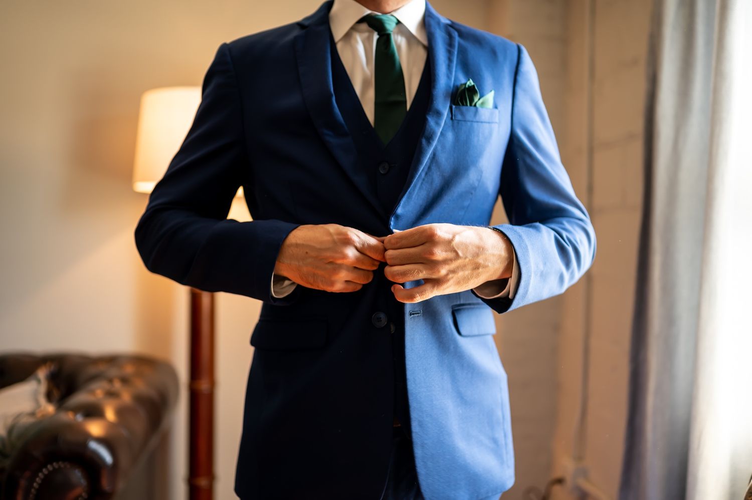 Business professionals in suits stand together in an office with warm lighting, cropped to show their formal attire.