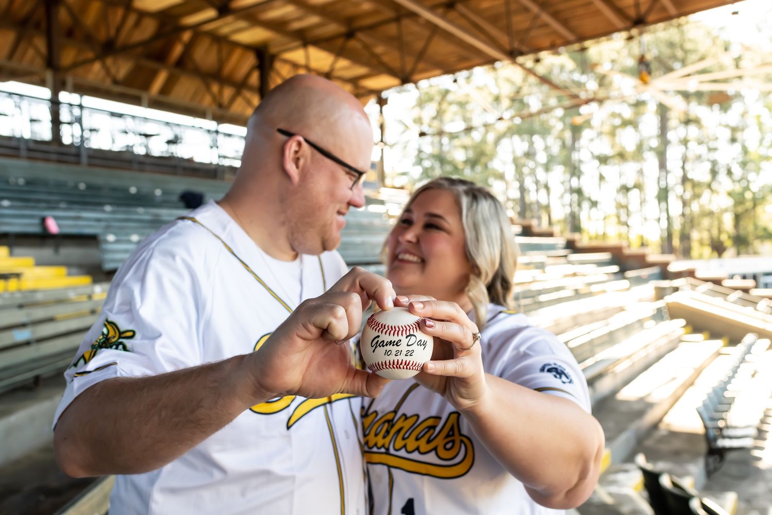 Happy couple sharing milkshakes at outdoor stadium bleachers on a sunny afternoon.