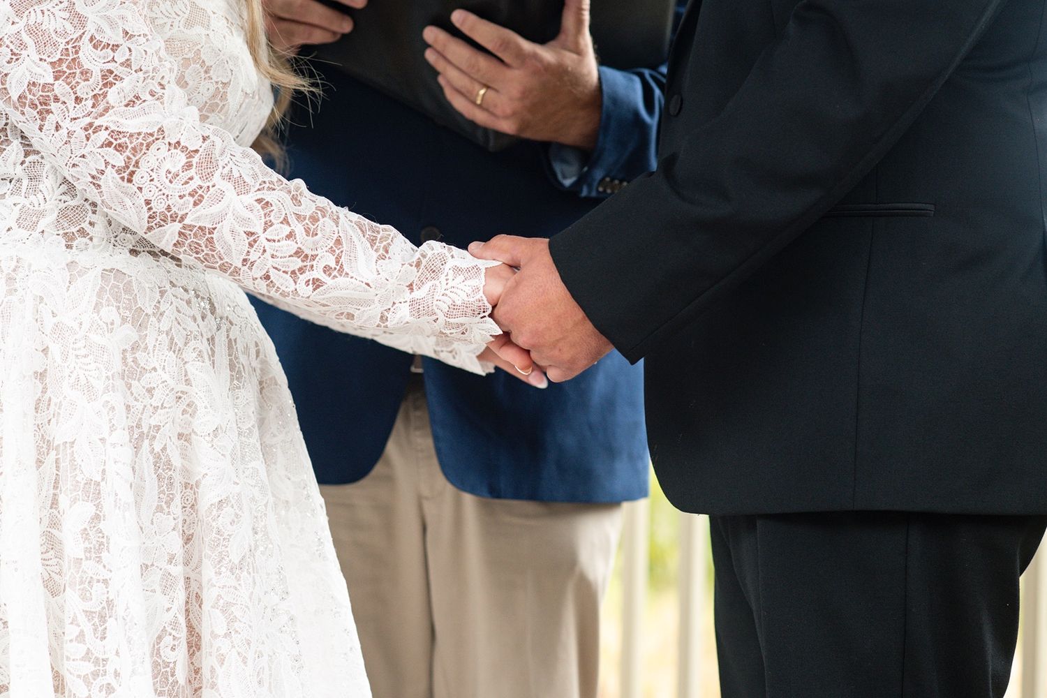 People in formal attire standing together with hands clasped at a ceremony.