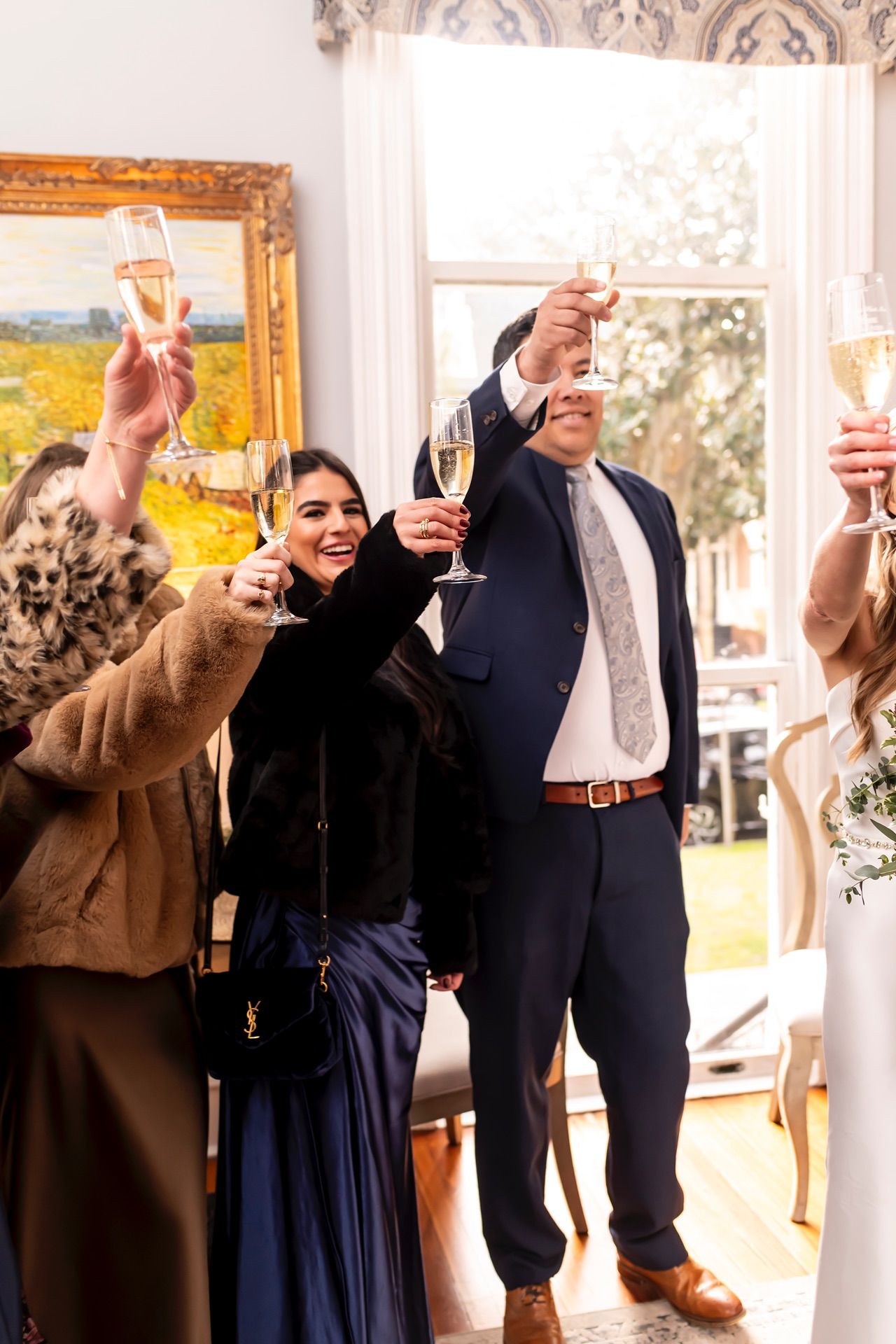 Three people raising champagne glasses in a formal toast at an elegant event in ornate room.