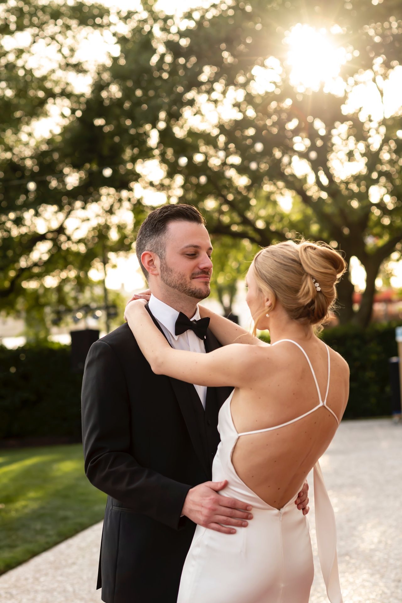 Newlyweds share an intimate sunset dance together in a garden setting.