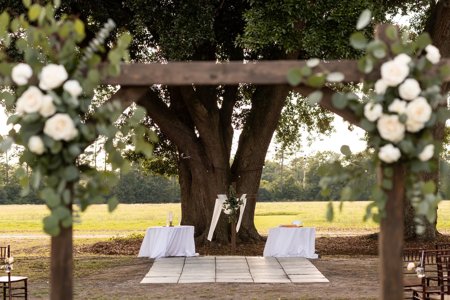 A rustic wooden picnic table sits under shady trees with soft bokeh lights and natural sunlight filtering through.