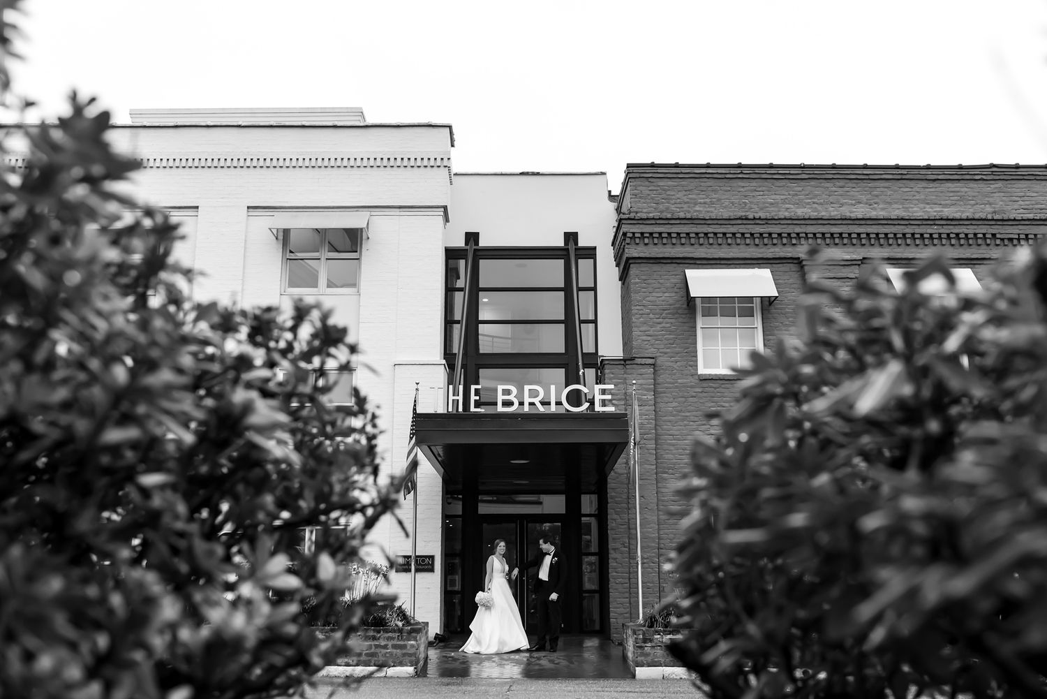 Black and white architectural panorama shows historic Main Street storefronts with vintage signage and brick details.