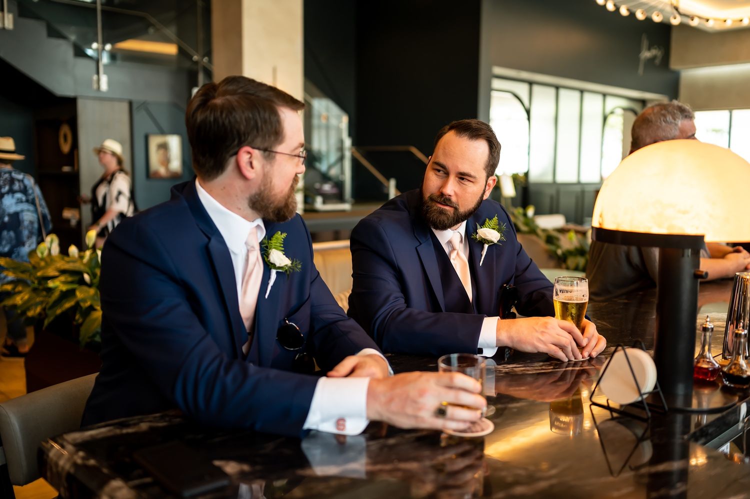 Two people in business attire meet at an office desk, sitting across from each other in discussion.