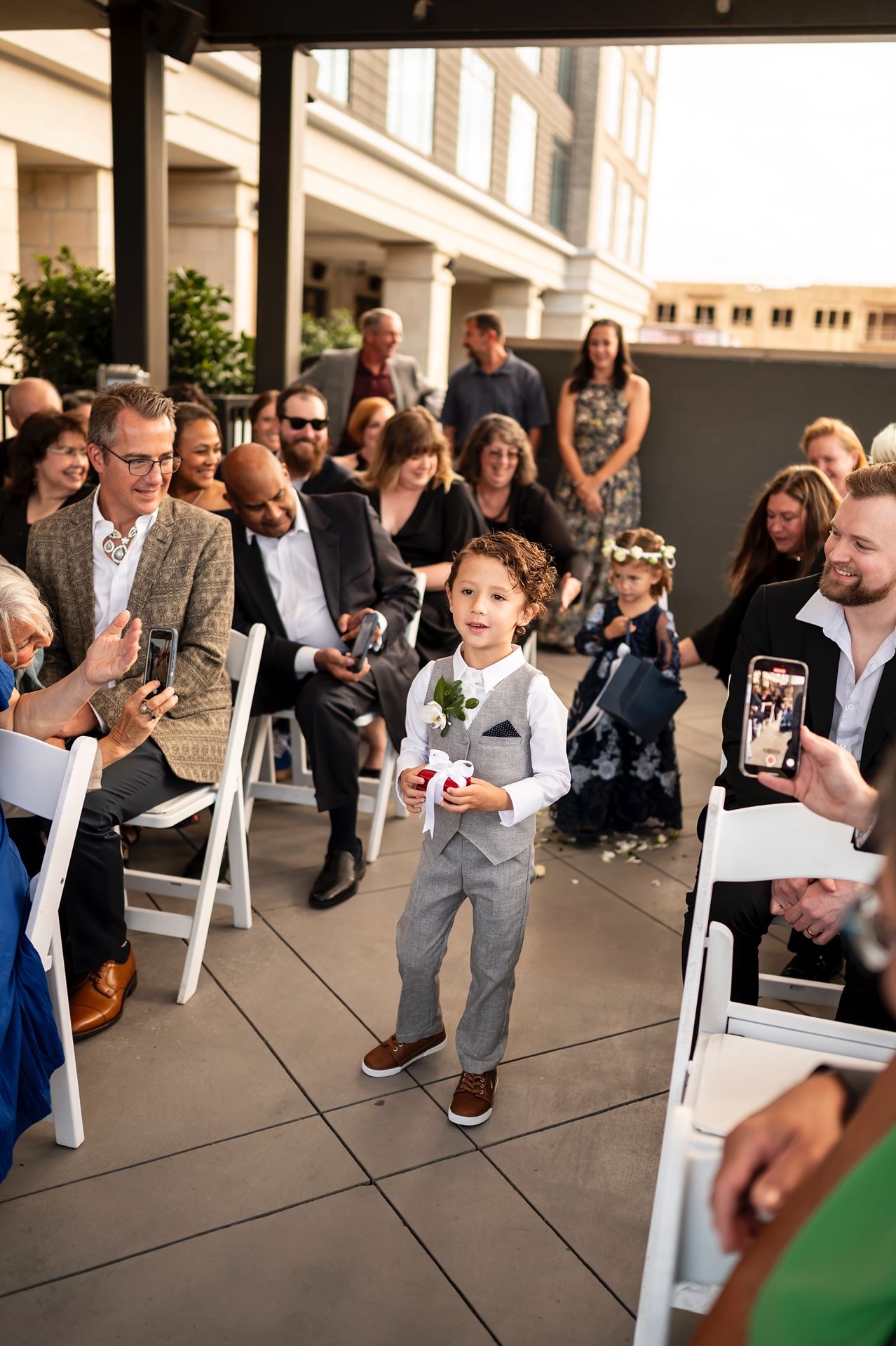 A group of guests gather outside at an outdoor venue with columns for an event.