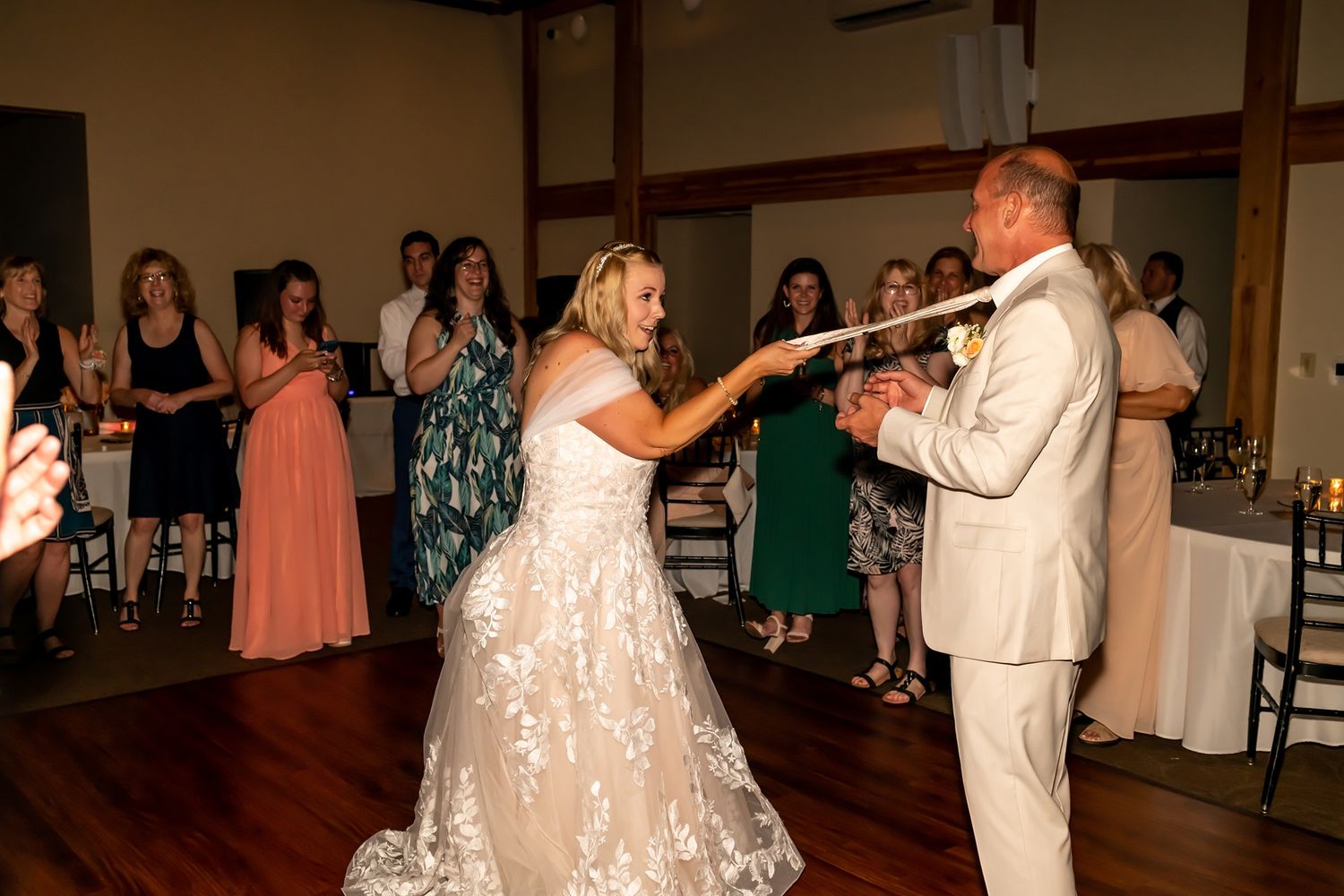 A couple shares a dance during their wedding reception as guests watch from the dance floor.
