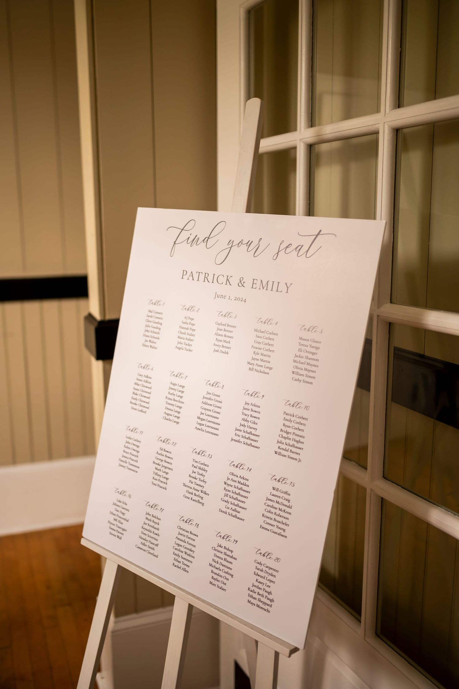Elegant wedding seating chart display with multiple white cards mounted on a wall showing guest table assignments.