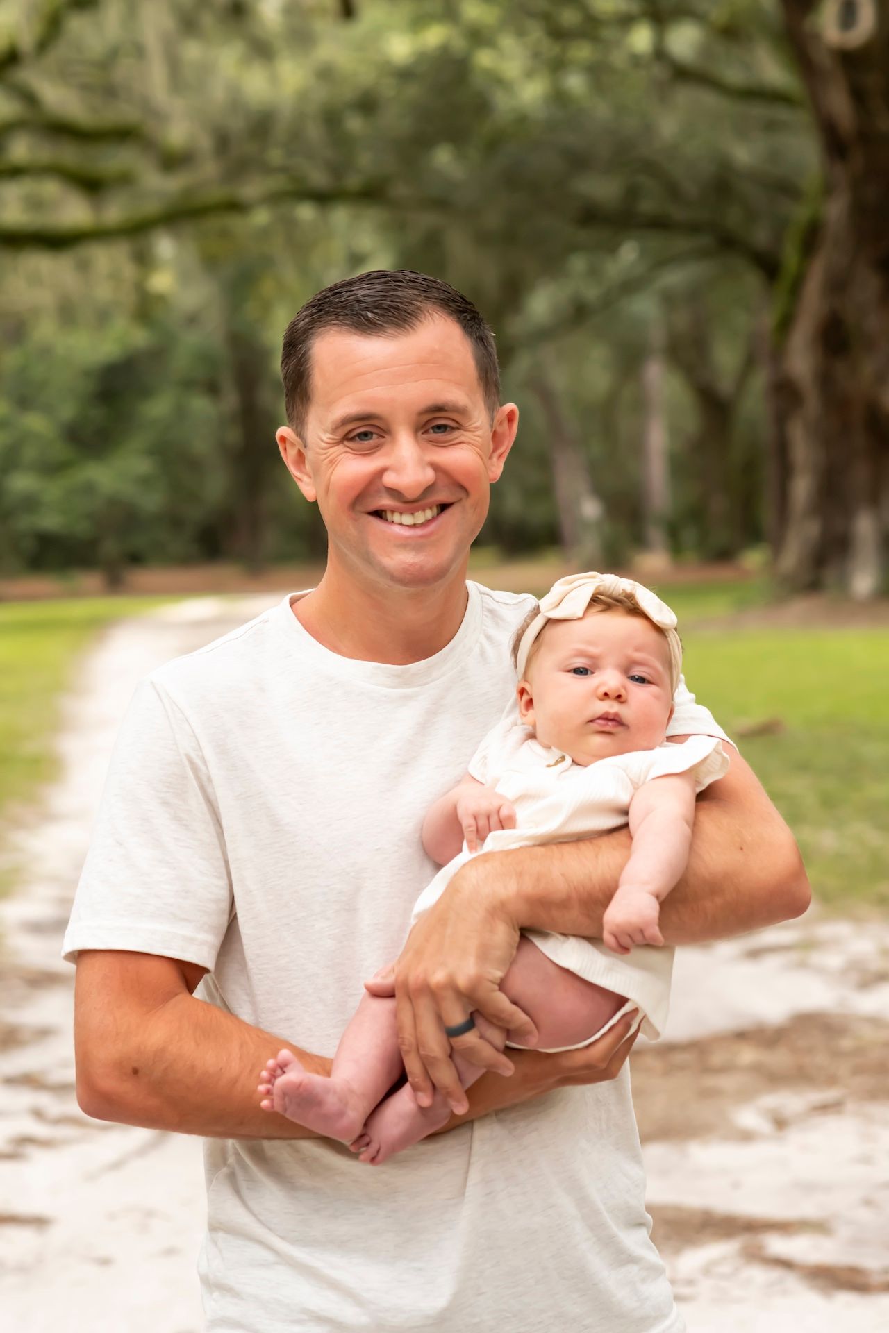A progression of five candid moments showing a person in white holding a baby outdoors in a natural setting.