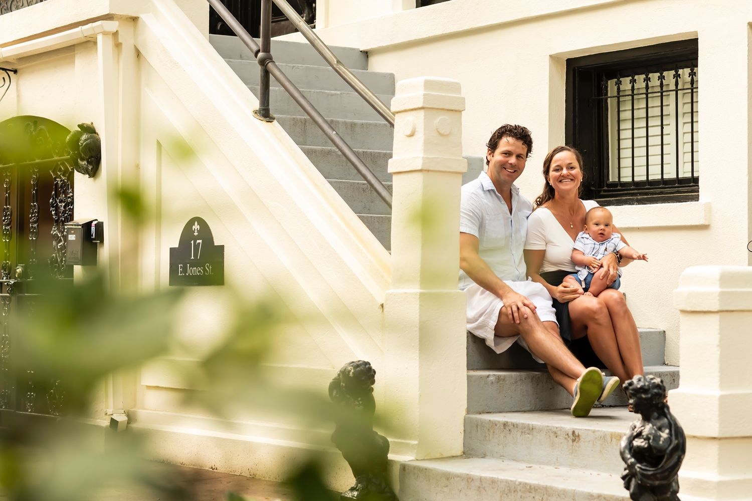Couple sitting together on white stone steps outside a residential building on a sunny day.