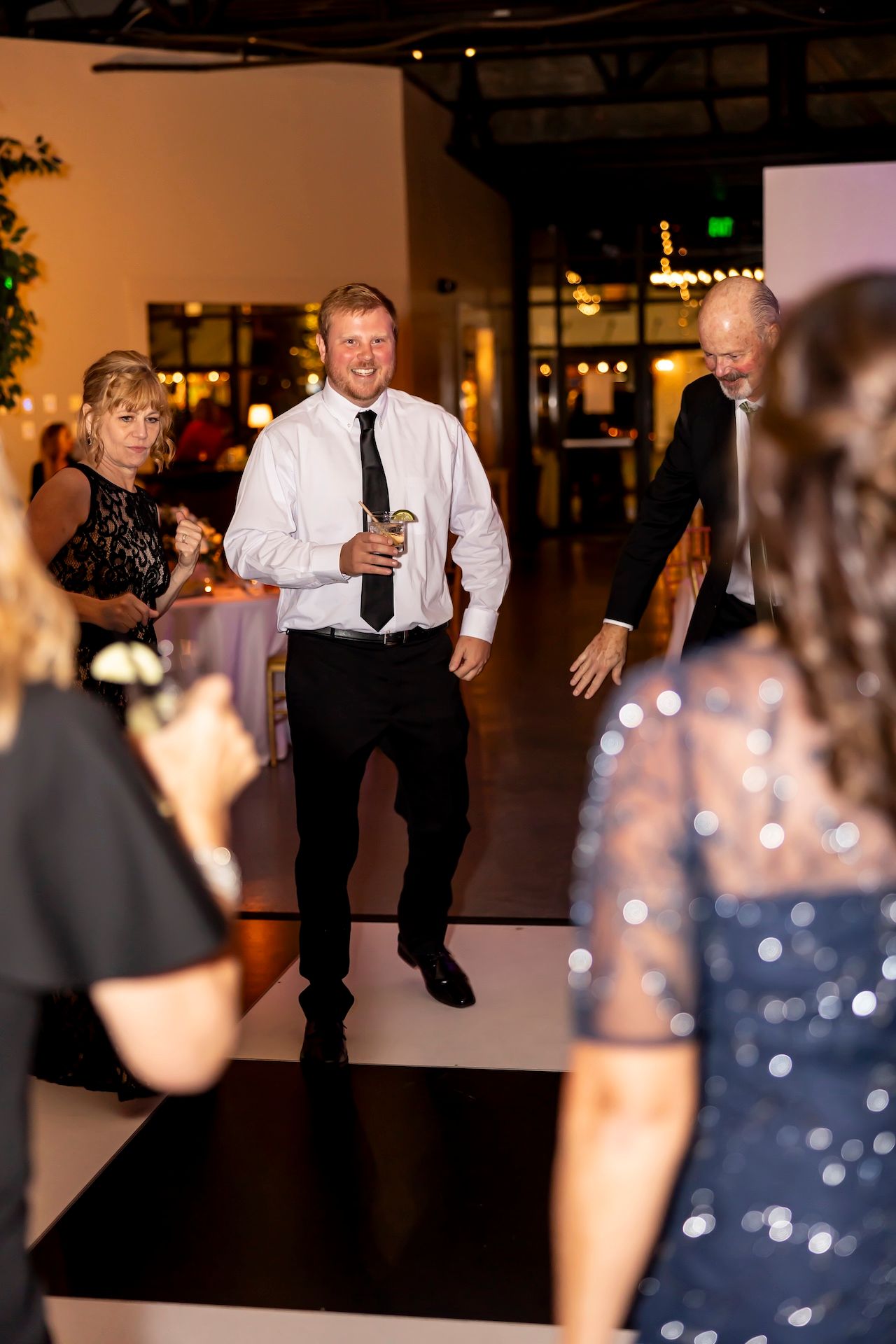 A guest shows off energetic dance moves on the dance floor at an indoor evening reception event.