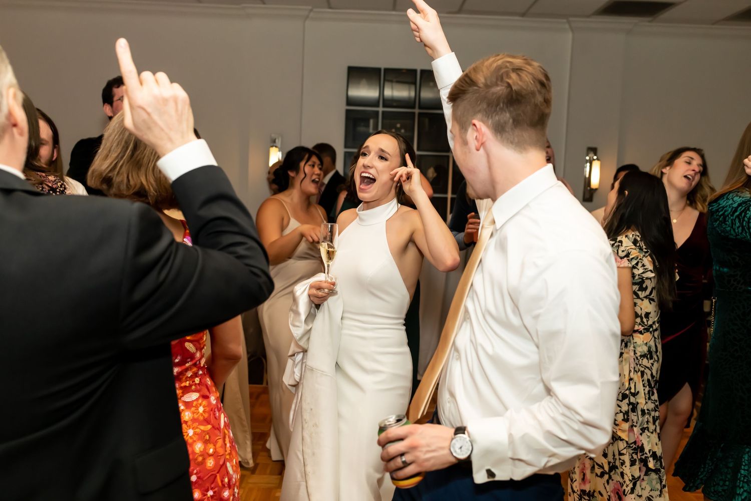 Wedding guests on a dance floor celebrate and dance together at a reception party with joyful energy.