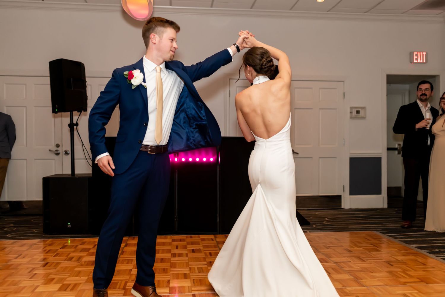 A couple in wedding attire dances together during their first dance reception on a wooden dance floor.