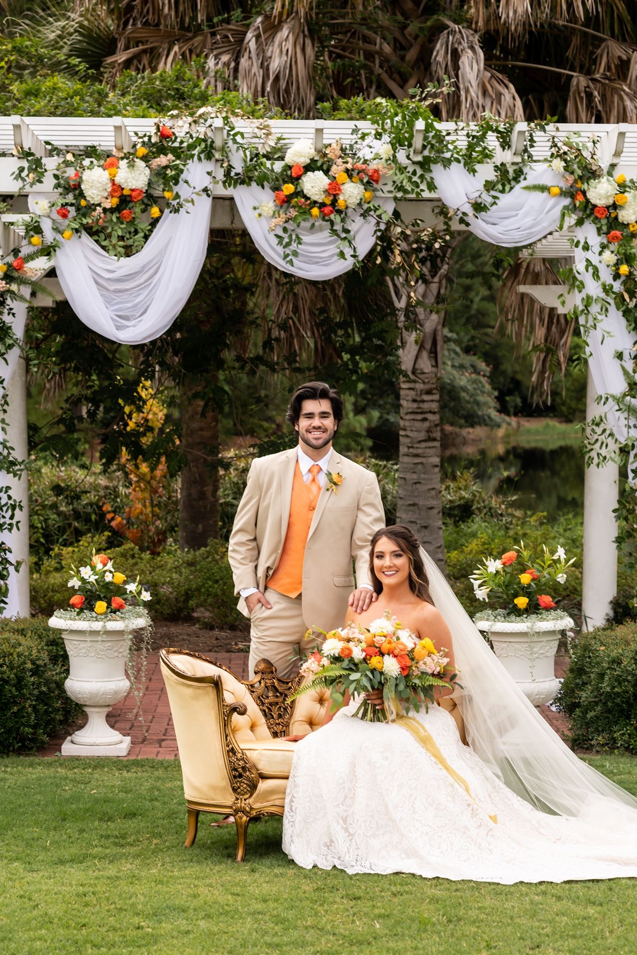 Romantic outdoor wedding scene with white floral arch and tropical palm backdrop.