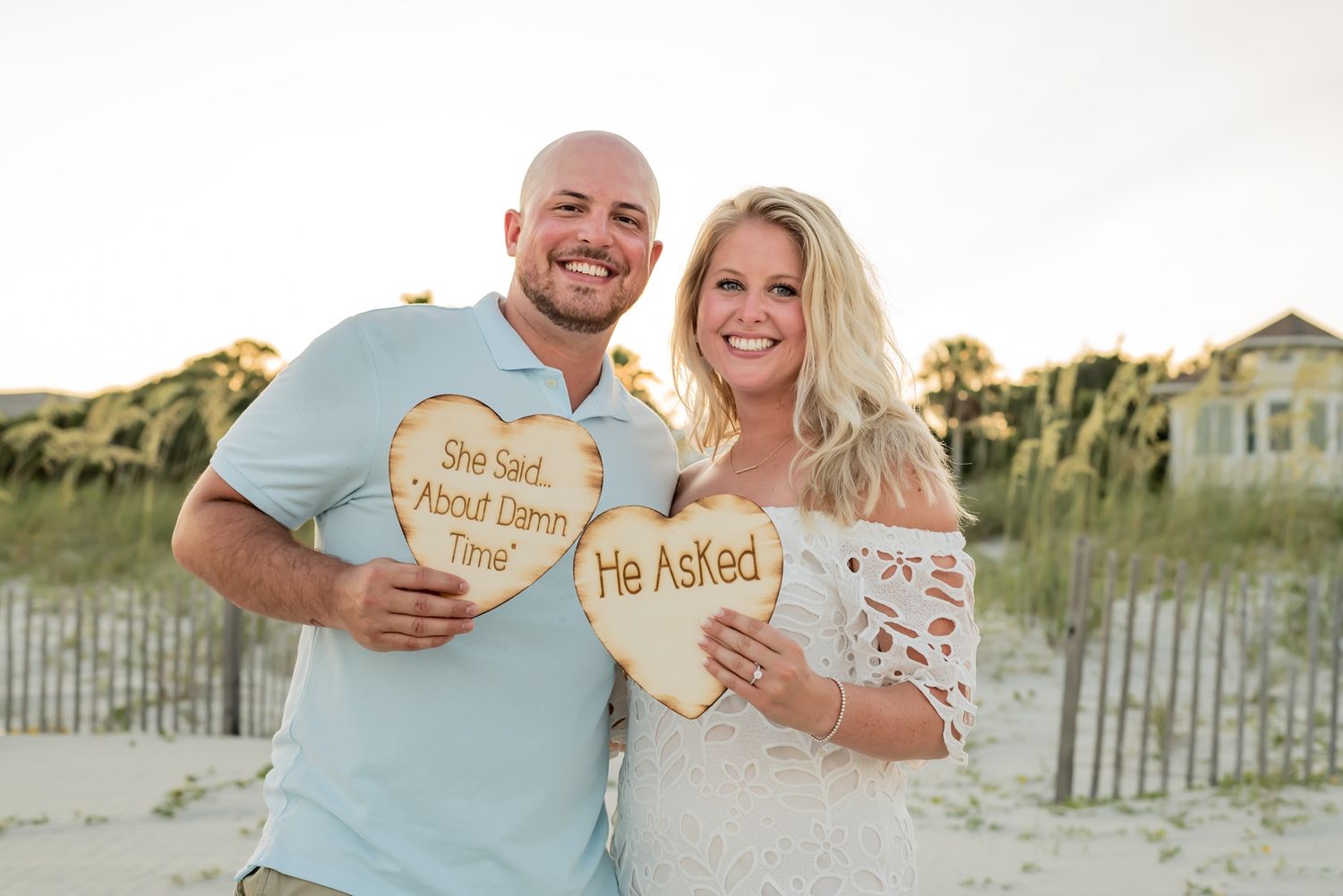 A couple holds wooden heart signs displaying 