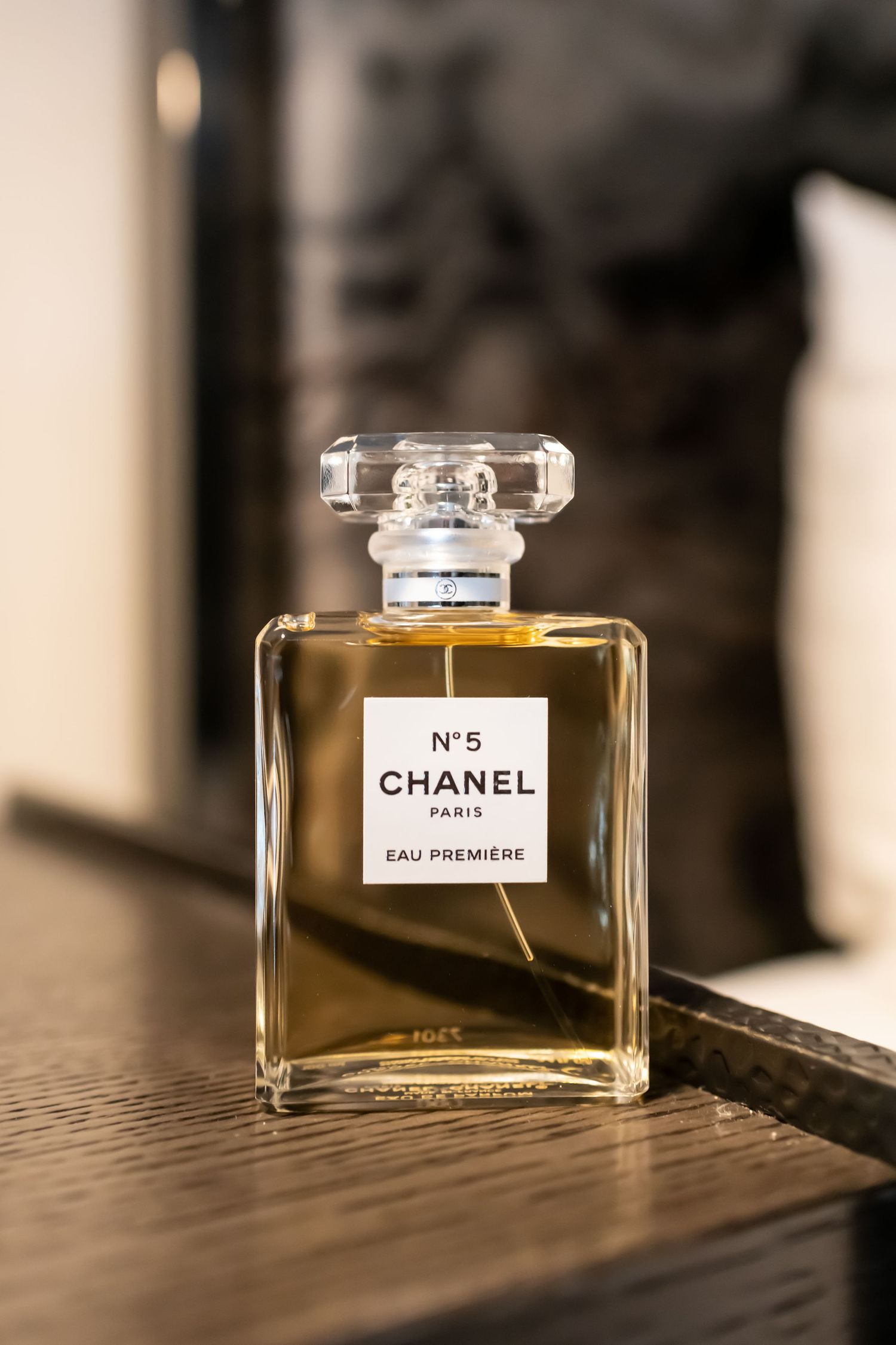 Classic Chanel No 5 perfume bottle displayed on wooden surface in warm lighting.