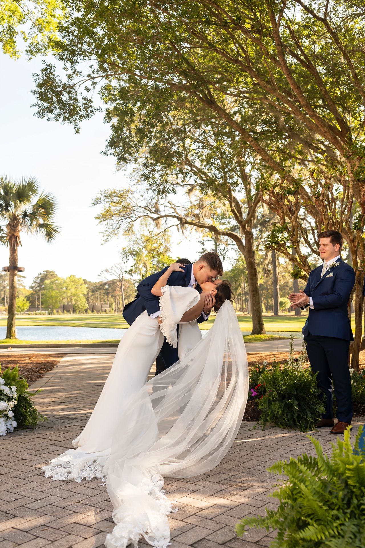 A romantic dip pose captured in sequence during a wedding photoshoot on a tree-lined pathway at sunset.