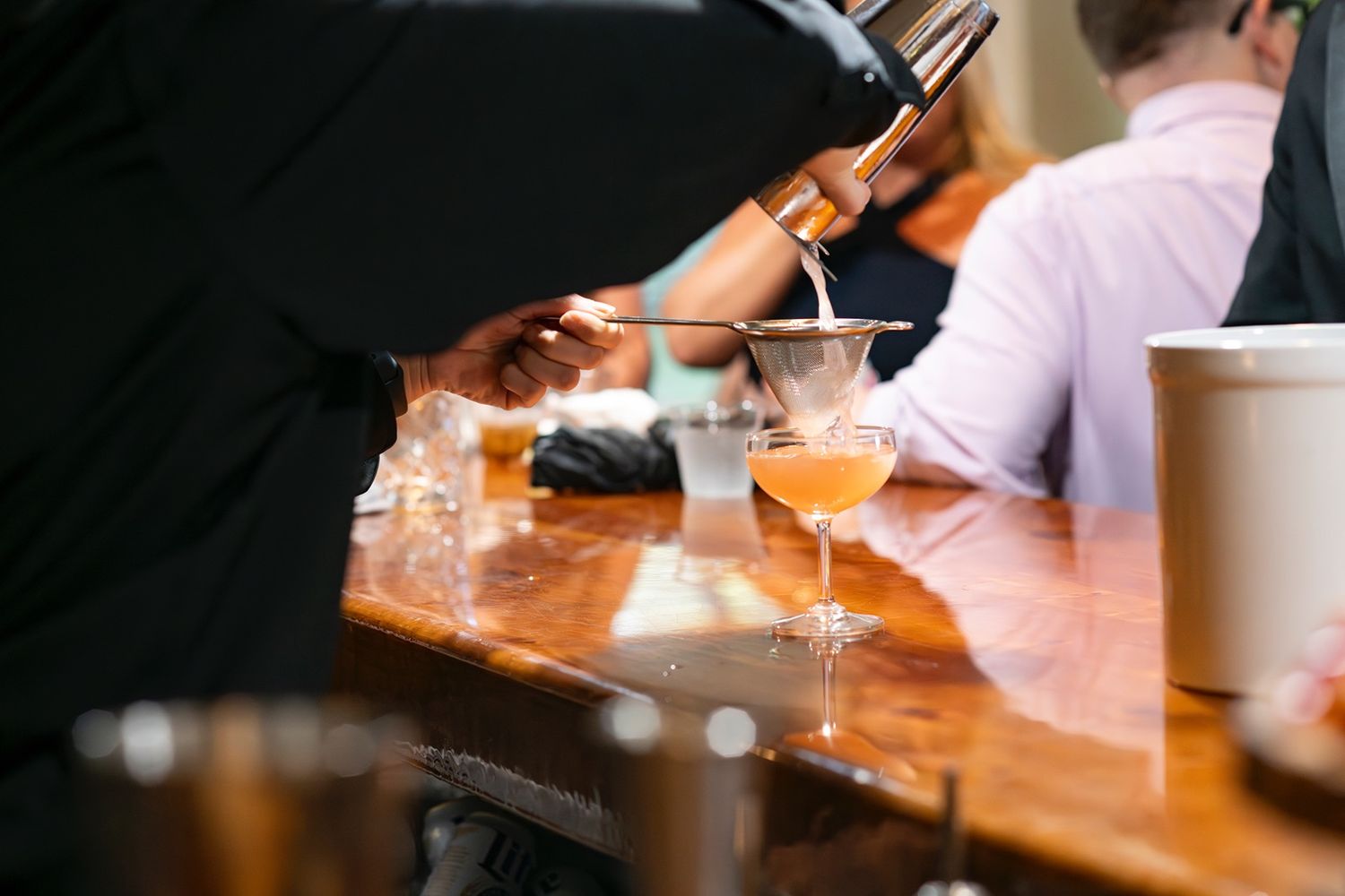 A wooden table setting at a restaurant with warm lighting and drinking glasses.