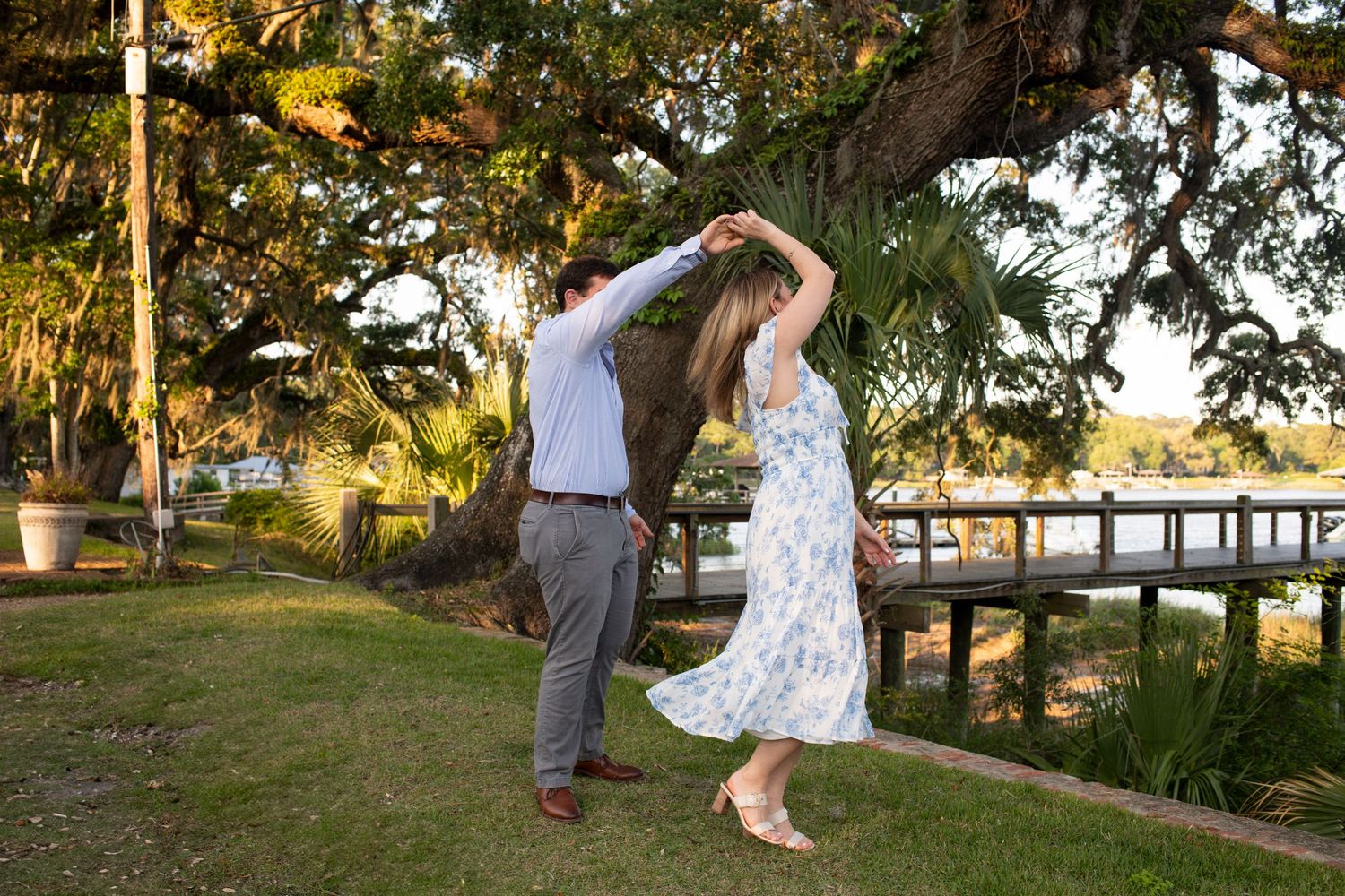 A couple dances together at sunset in a romantic outdoor garden setting with golden light filtering through trees.
