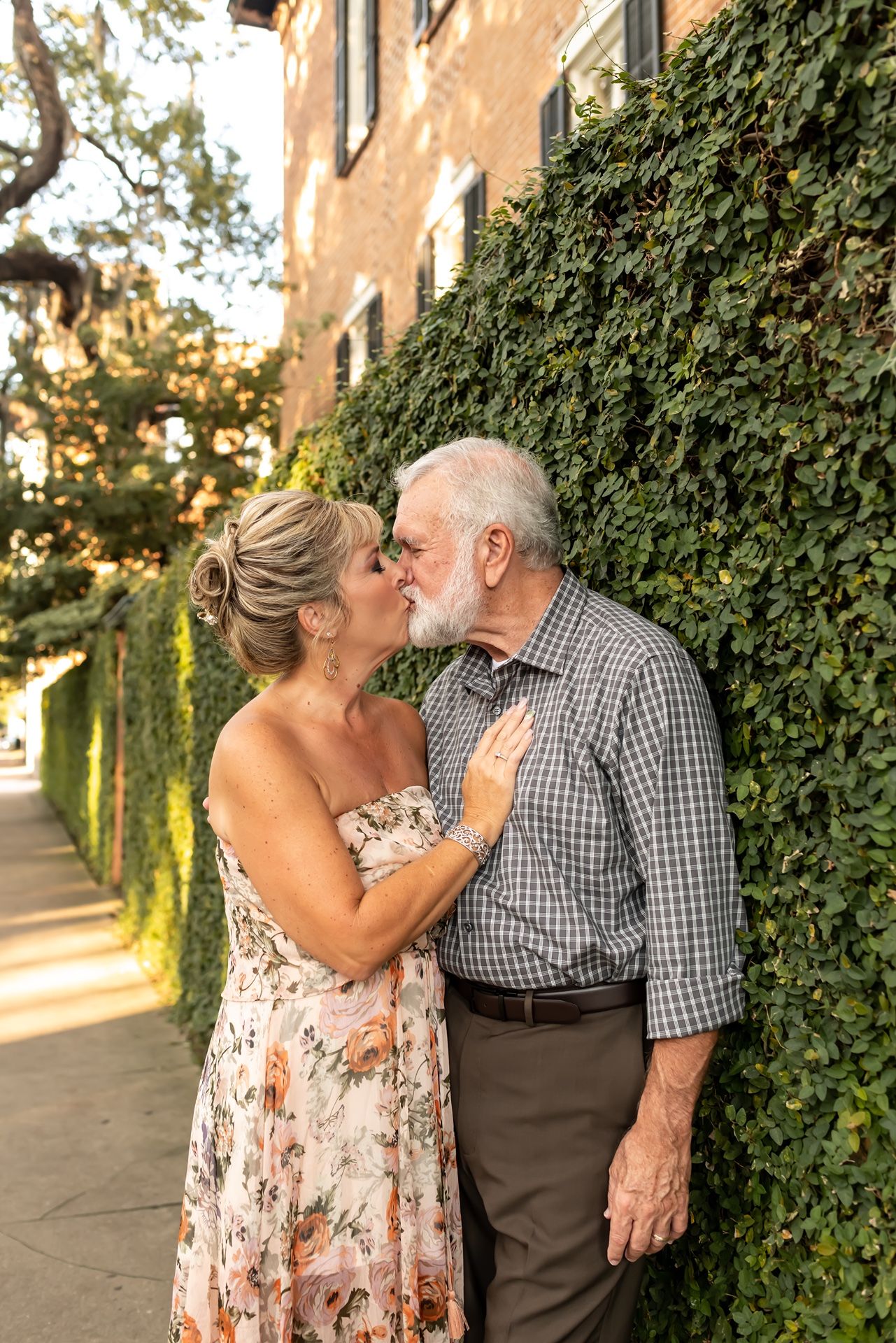 A romantic couple sharing a tender moment against an ivy-covered wall during golden hour.