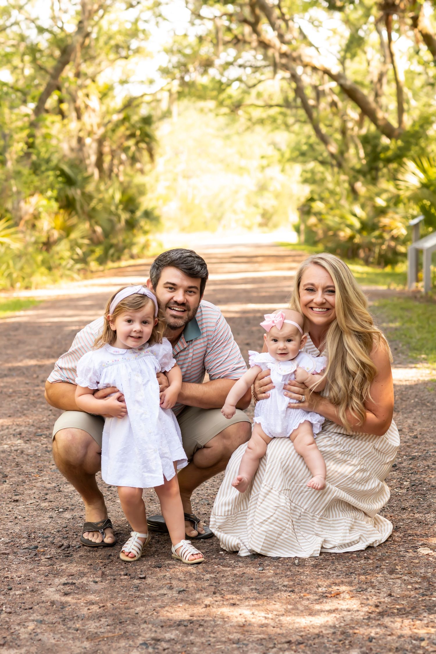 Family in coordinated white and beige outfits share joyful moments while sitting together on autumn ground.