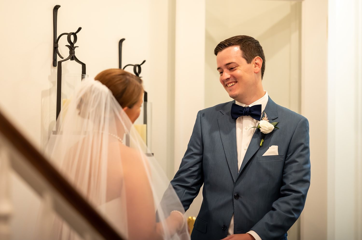 A couple exchanges loving looks during their first look wedding moment in a light-filled corridor.