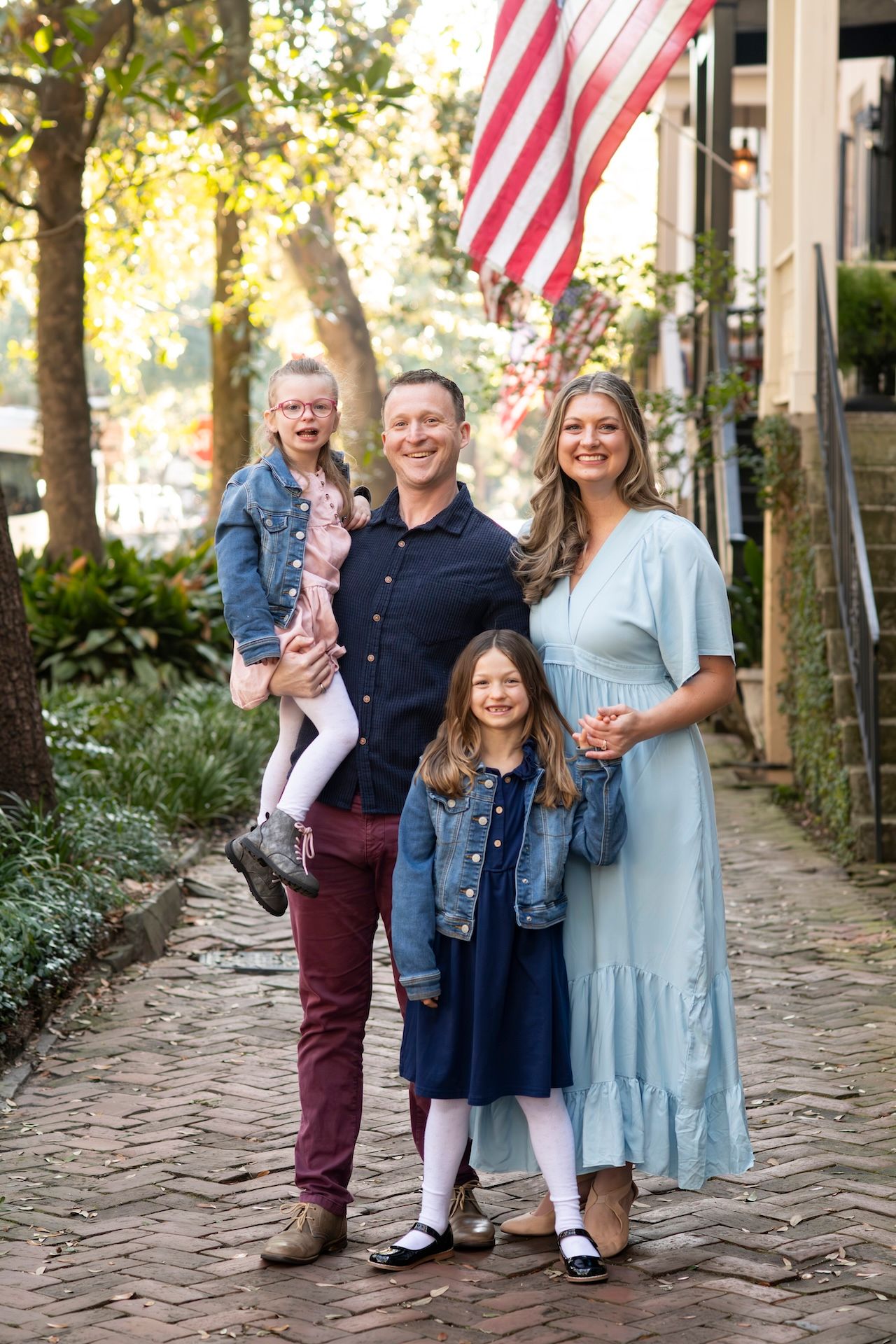 Family of four poses on a brick sidewalk on Jones Street in Savannah, Georgia.
