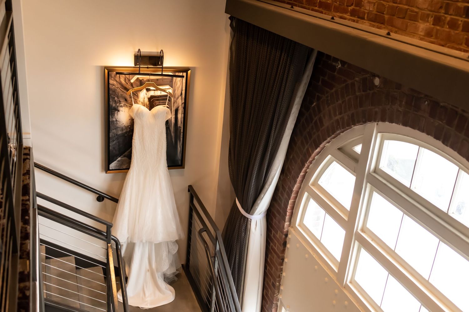 Interior view of wedding dress in elegant venue with arched windows and natural lighting.