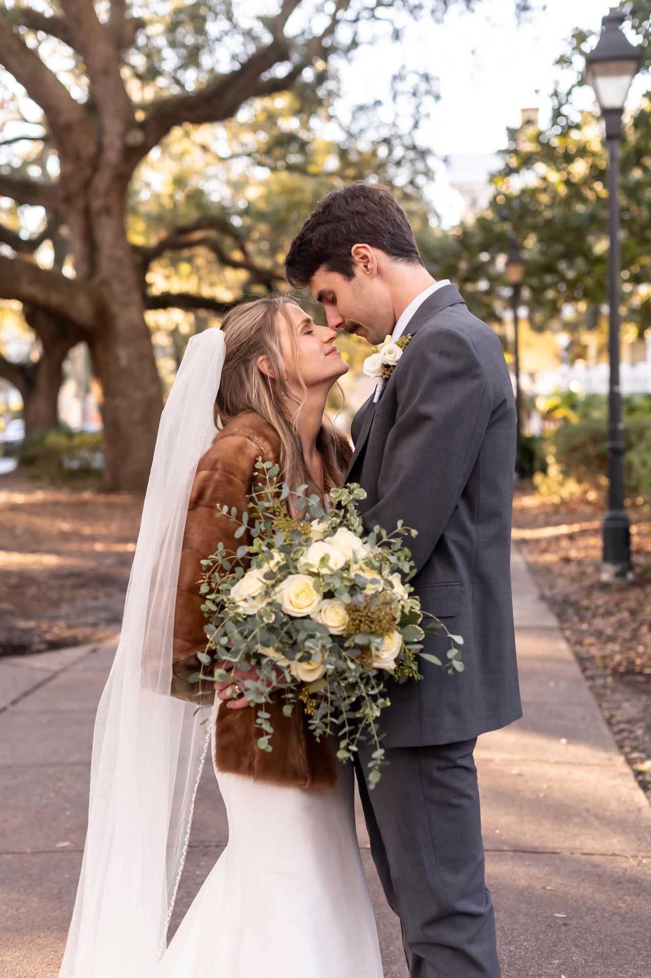 A romantic wedding couple shares intimate moments in Forsyth Park during golden hour.