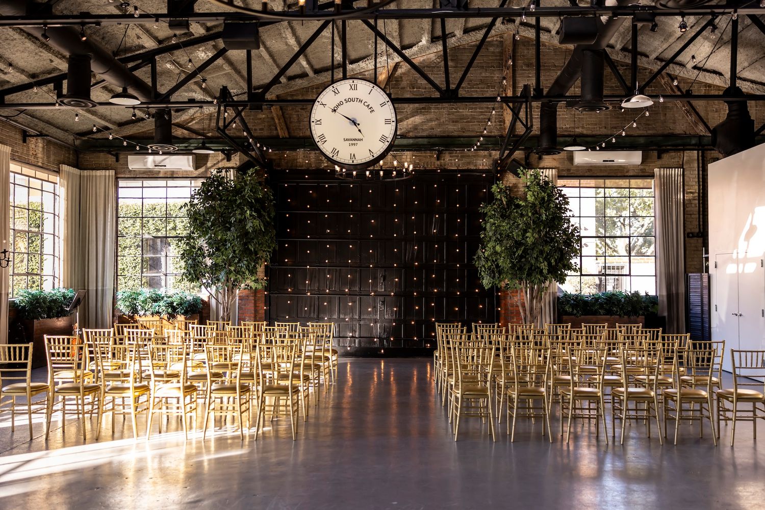 Panoramic view of a large industrial event space with rustic wooden beams and hanging light fixtures.