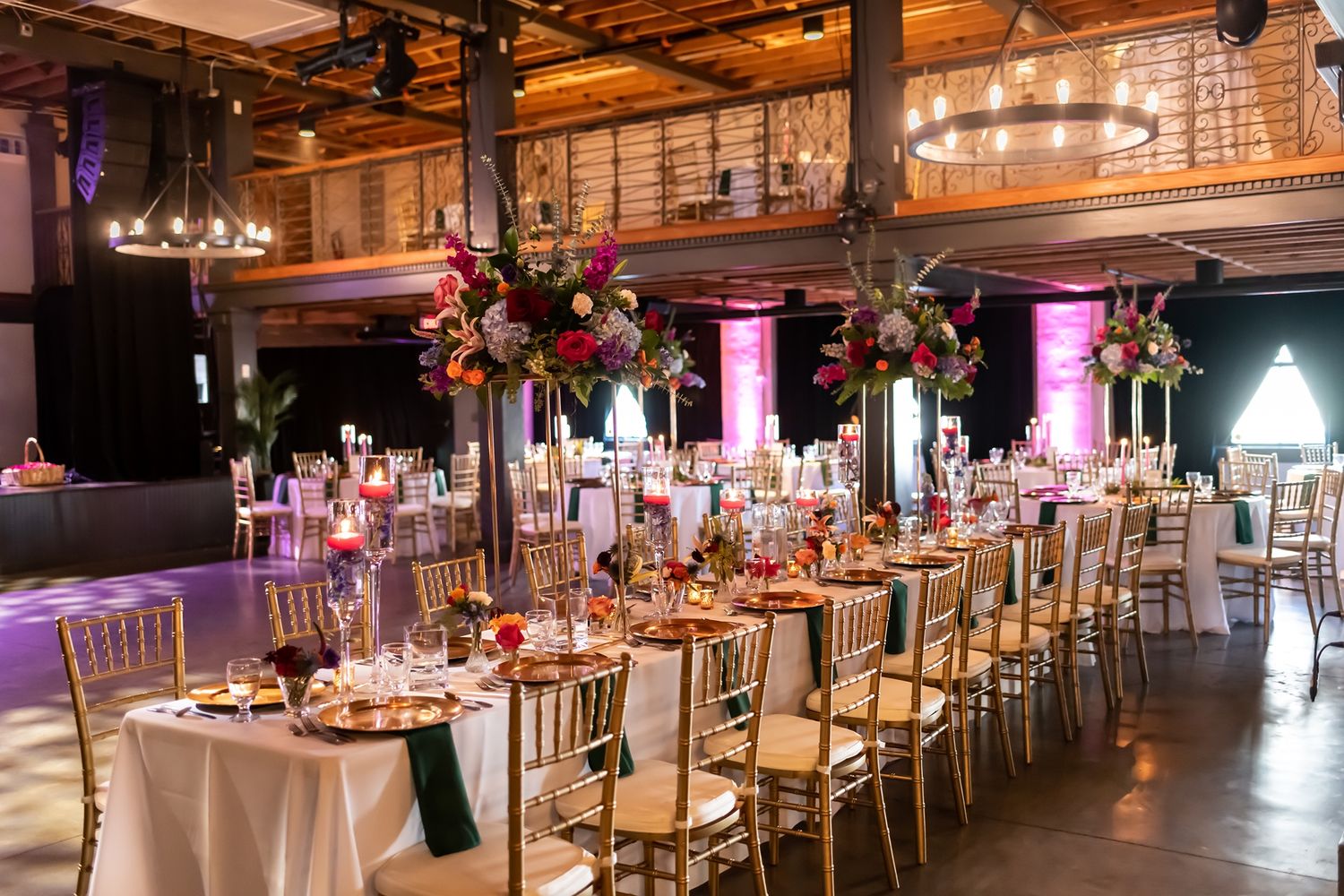 Elegant wedding reception hall with rustic wood beams, warm lighting, and long tables set for a formal dining celebration.