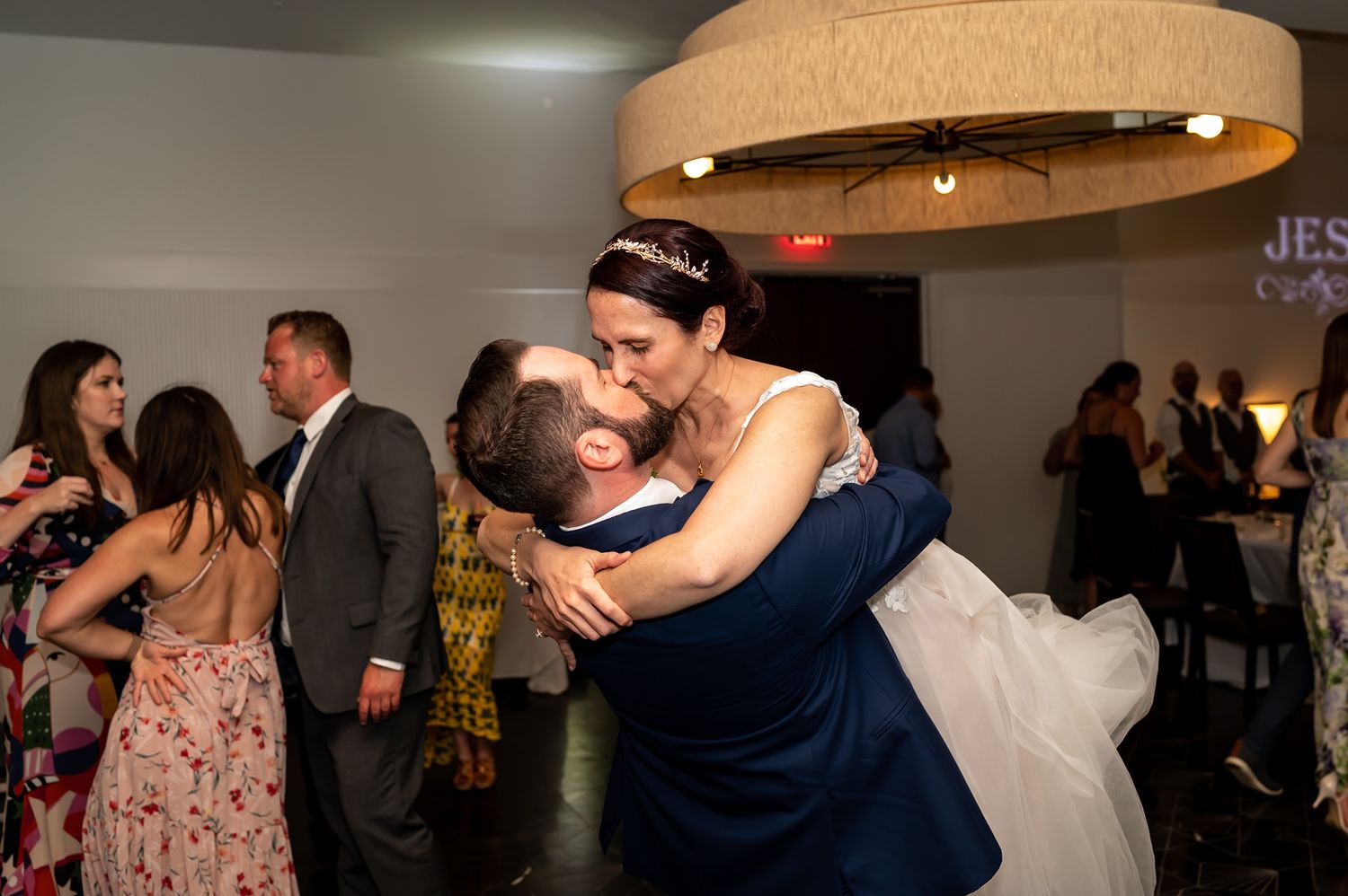 A joyful dancing moment captured at a wedding reception with guests celebrating in the background.