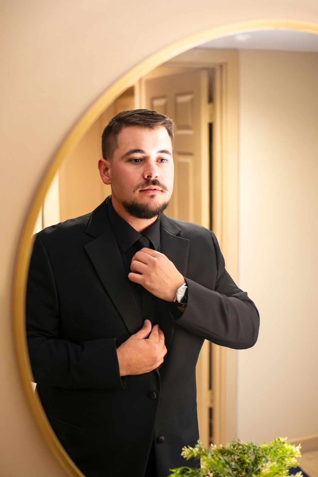A sequence of photos showing someone adjusting a black suit jacket in front of a round mirror.